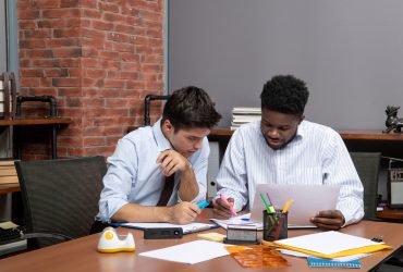 front-view-work-process-two-businessmen-discussing-project-while-sitting-desk